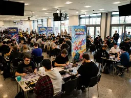 Illustrationsfoto med Pokémon-spillere ved borde i en hal.
